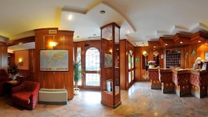 A lobby with a reception desk, seating area, and a large map on the wall. - Hotel Vela (Trento)