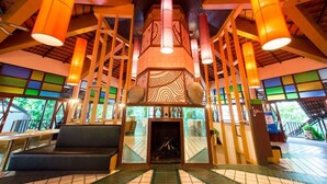 A spacious lobby with a central fireplace, high ceilings with exposed beams, and large windows allowing natural light. - The Greenery Resort Khao Yai (Pak Chong)