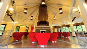 A spacious lobby with a high ceiling, a fireplace, and red seating areas. - The Greenery Resort Khao Yai (Pak Chong)