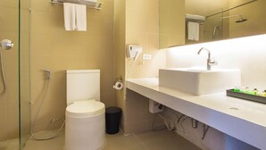 A modern bathroom with a white sink, a glass shower enclosure, a toilet, and a towel rack. - The Greenery Resort Khao Yai (Pak Chong)