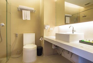 Uma casa de banho moderna com uma pia branca, cabine de duche em vidro, sanita e um porta-toalhas.