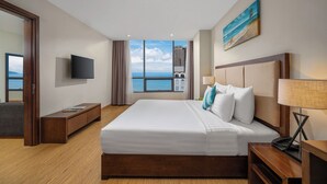A hotel room with a large bed, a TV, a desk, and a view of the sea. - Avatar Danang (Da Nang)