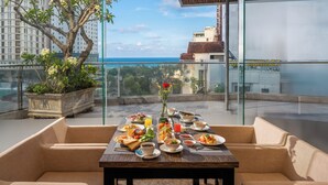 A dining table set with various dishes and a potted plant on a balcony with a city view. - Avatar Danang (Da Nang)