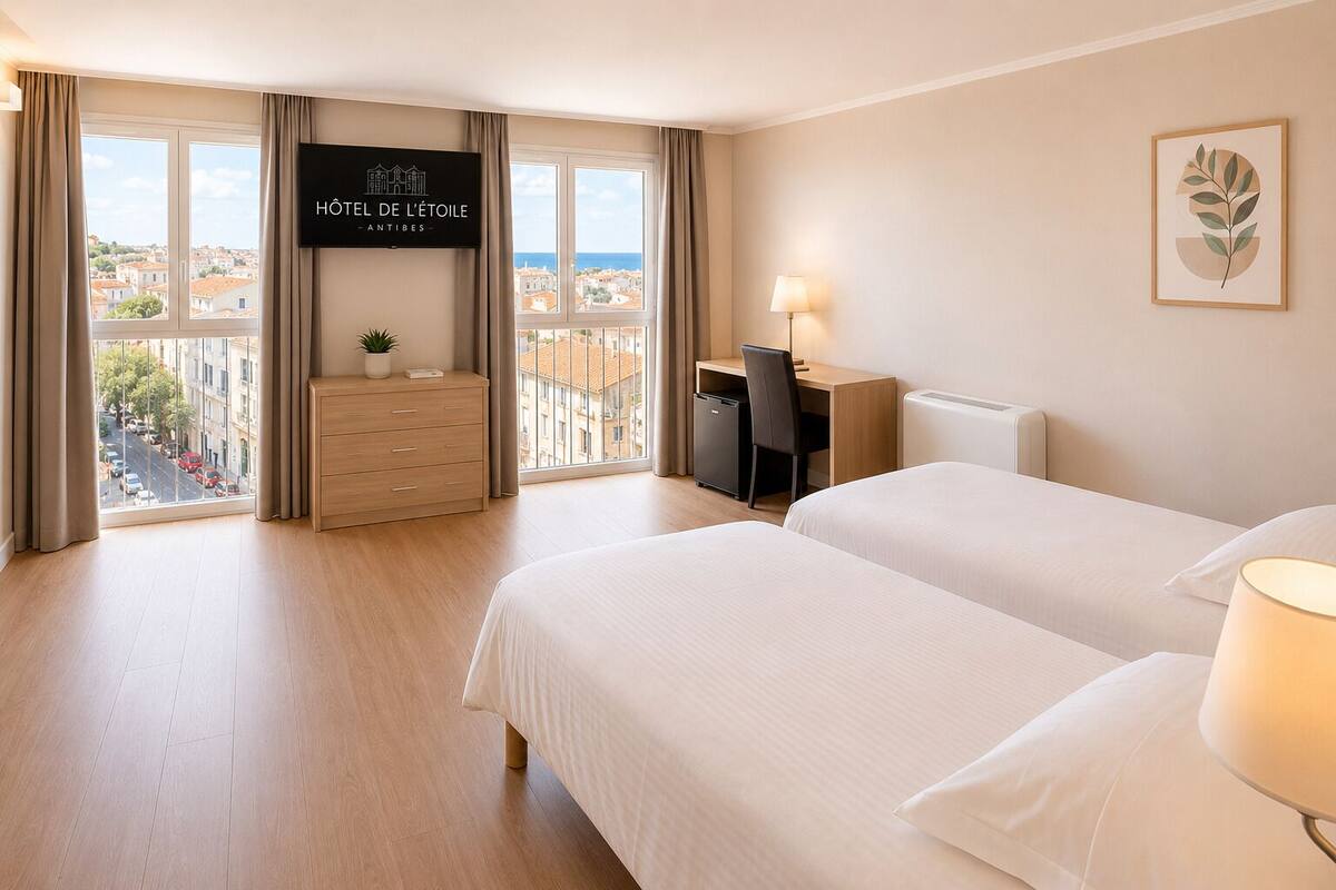 A hotel room with two beds, a desk, a dresser, a TV, and a view of the city.