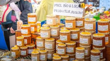 Exhibición de frascos de miel en un puesto de mercado con un cartel que indica que es un producto local.