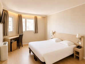 Una habitación de hotel con cama, escritorio, silla y un calentador.
