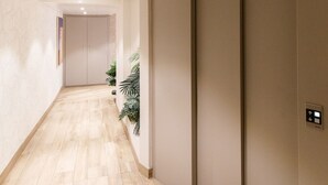 Un pasillo con suelo de madera, una puerta corredera e iluminación empotrada en el techo.