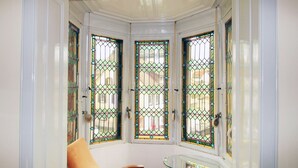 A corner room with a glass table, a brown chair, and three stained glass windows. - Hotel Neustädter Hof (Titisee-Neustadt)