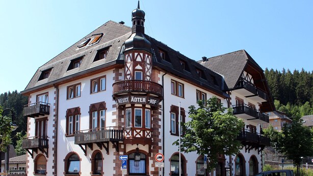 A traditional building with a corner turret, multiple balconies, and a sign indicating a parking area. - Hotel Neustädter Hof (Titisee-Neustadt)