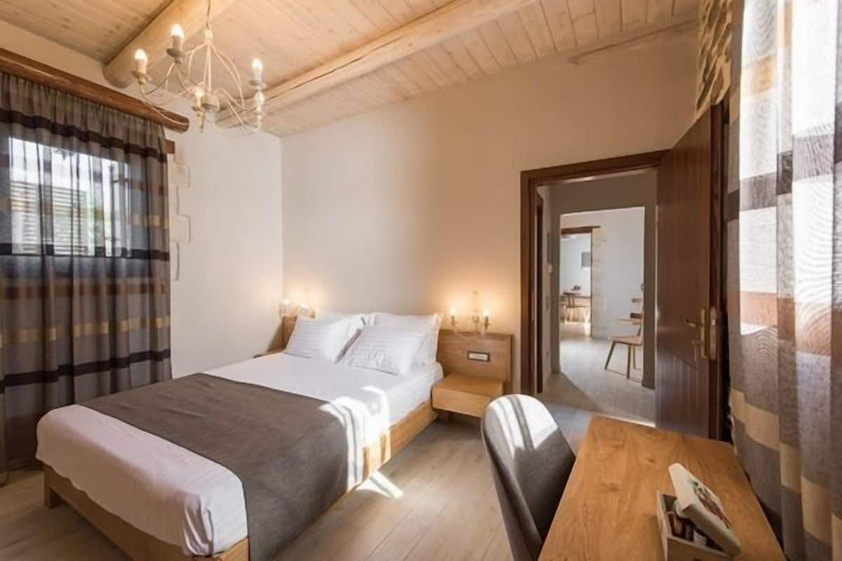 Een slaapkamer met een bed, nachtkastjes, een houten bureau en een kroonluchter.