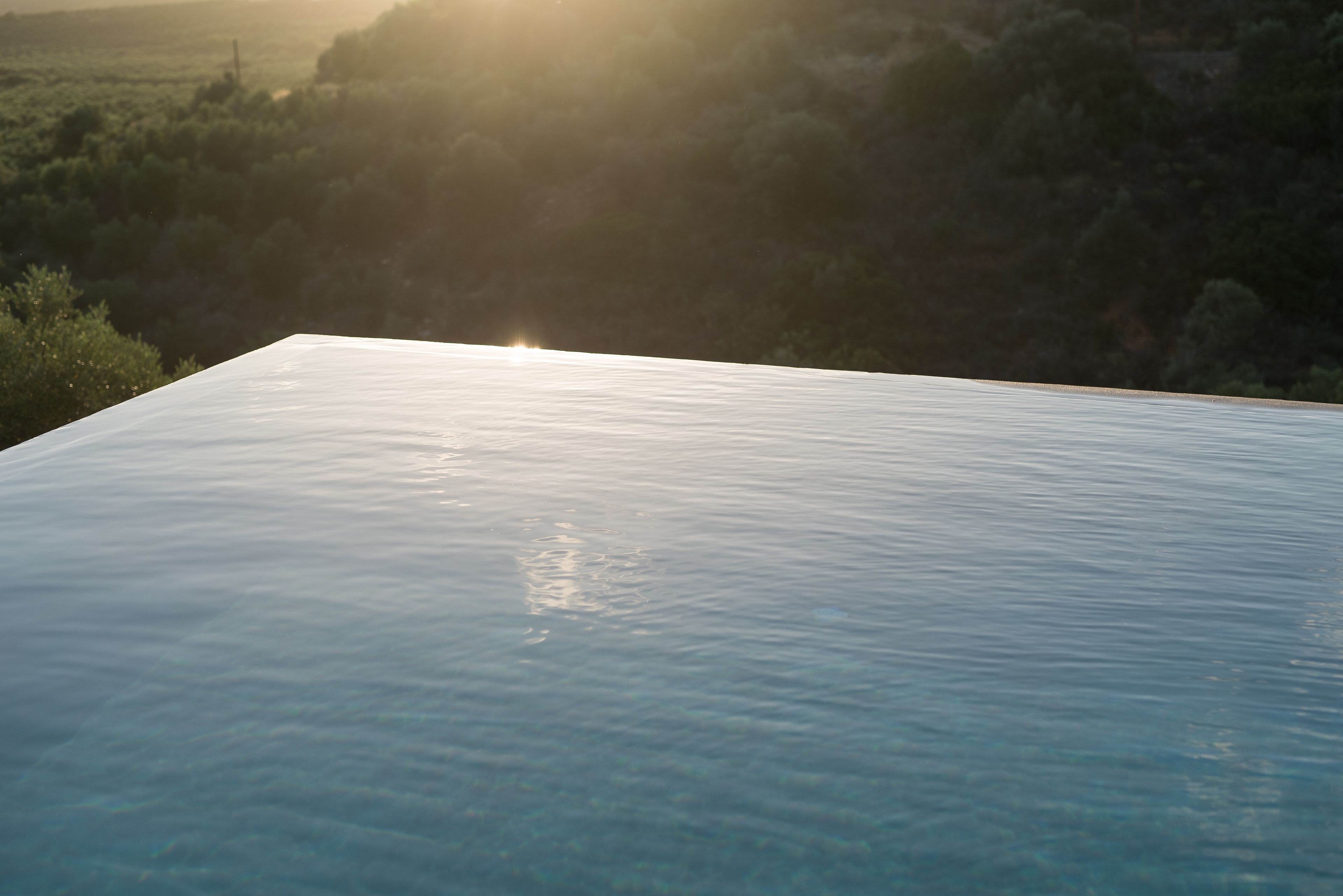 Une piscine à l’eau claire, avec une vue sur un paysage naturel en arrière-plan.