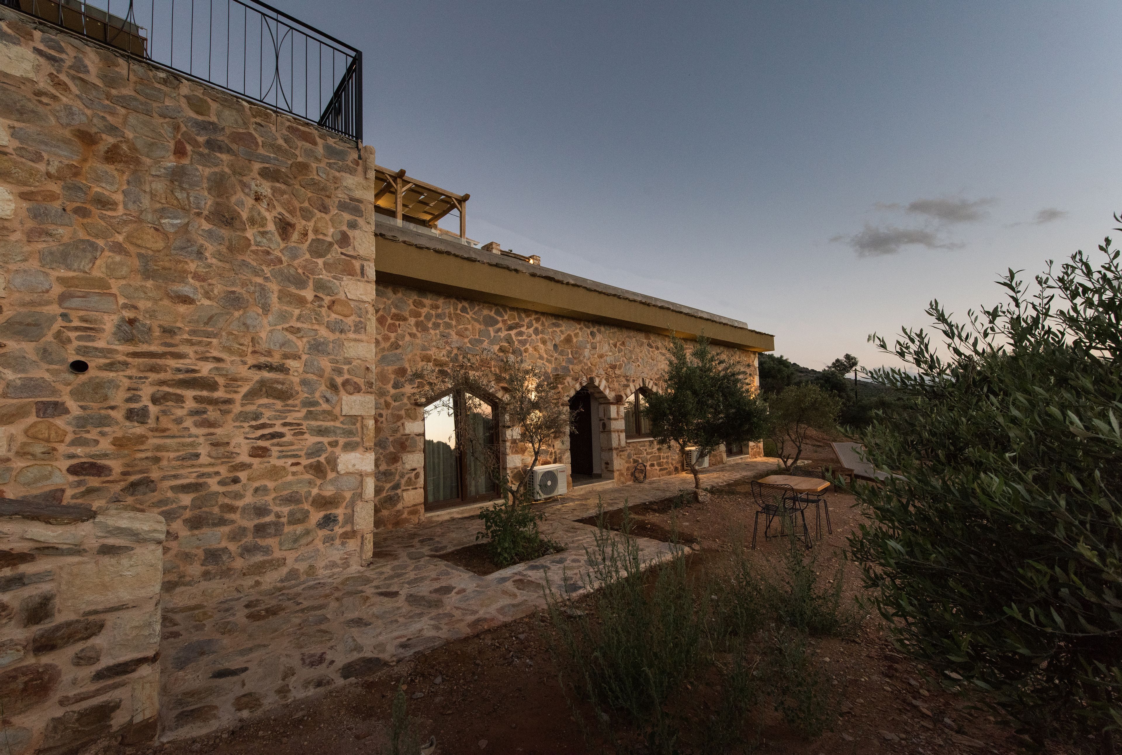 A stone building with a courtyard, featuring a balcony and outdoor seating area.