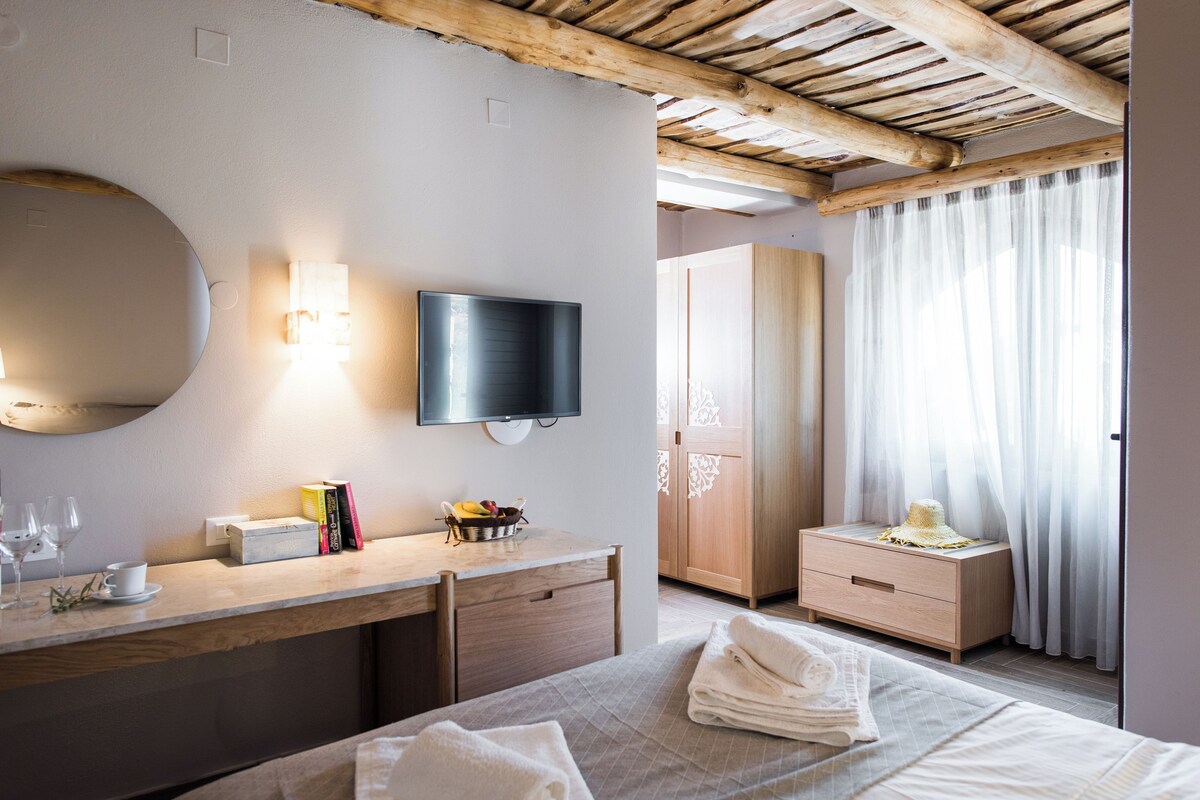 Een hotelkamer met een bed, een bureau met een flatscreen televisie, een spiegel en een raam met gordijnen.