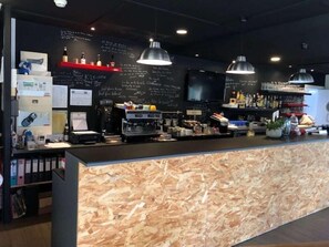 Un área de bar con mostrador, taburetes y una pizarra de menú.