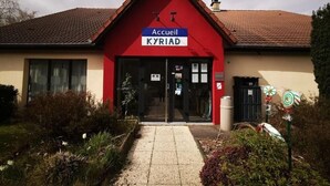 Ein Gebäude mit roter Fassade und einem Ziegeldach, mit der Aufschrift "Accueil KYRIAD".