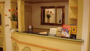 A reception area with a counter, a vase of flowers, a mirror, and a window. - Alpenschlössl (Mayrhofen)