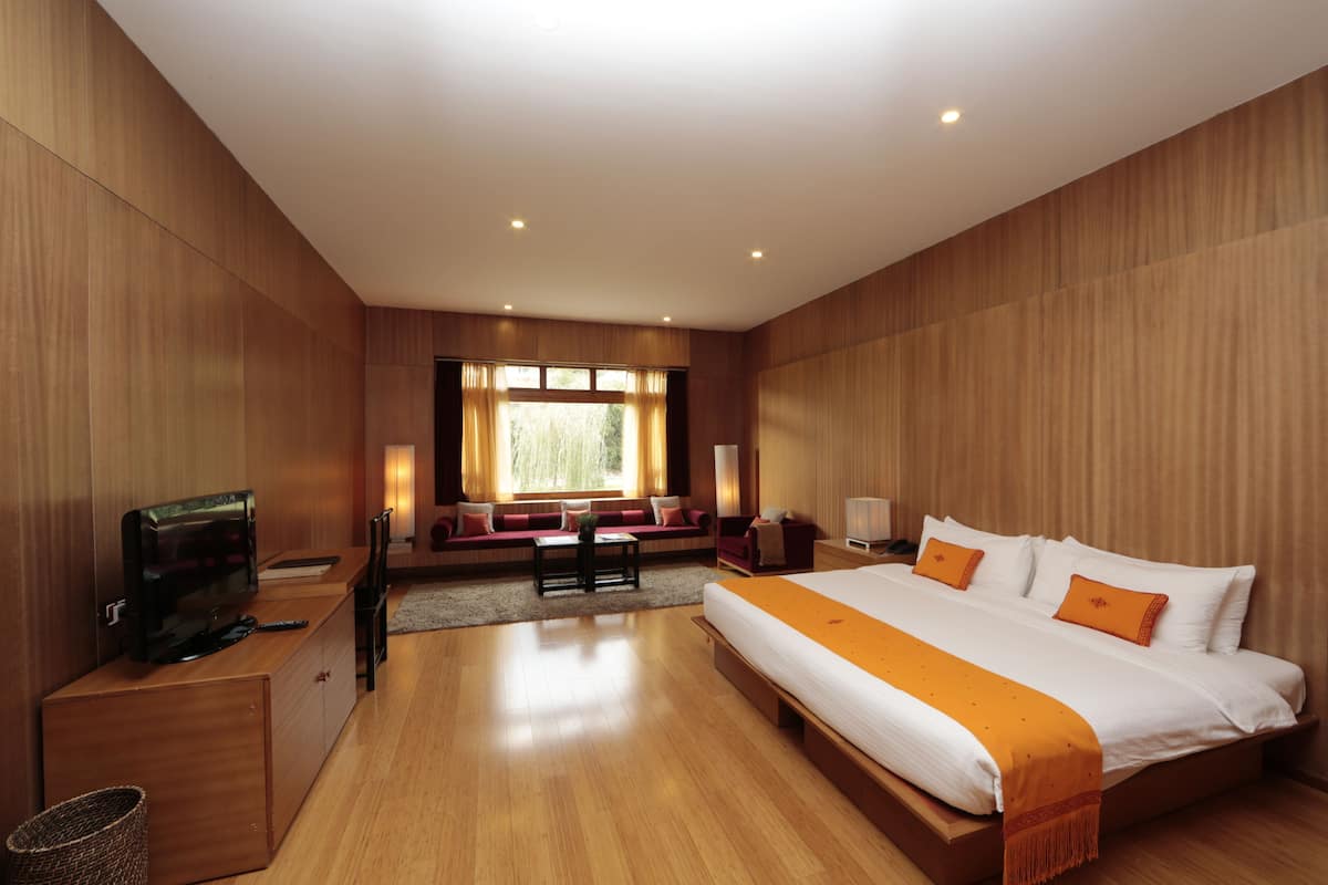A modern hotel room with a large bed, a TV, a desk, and a sofa.