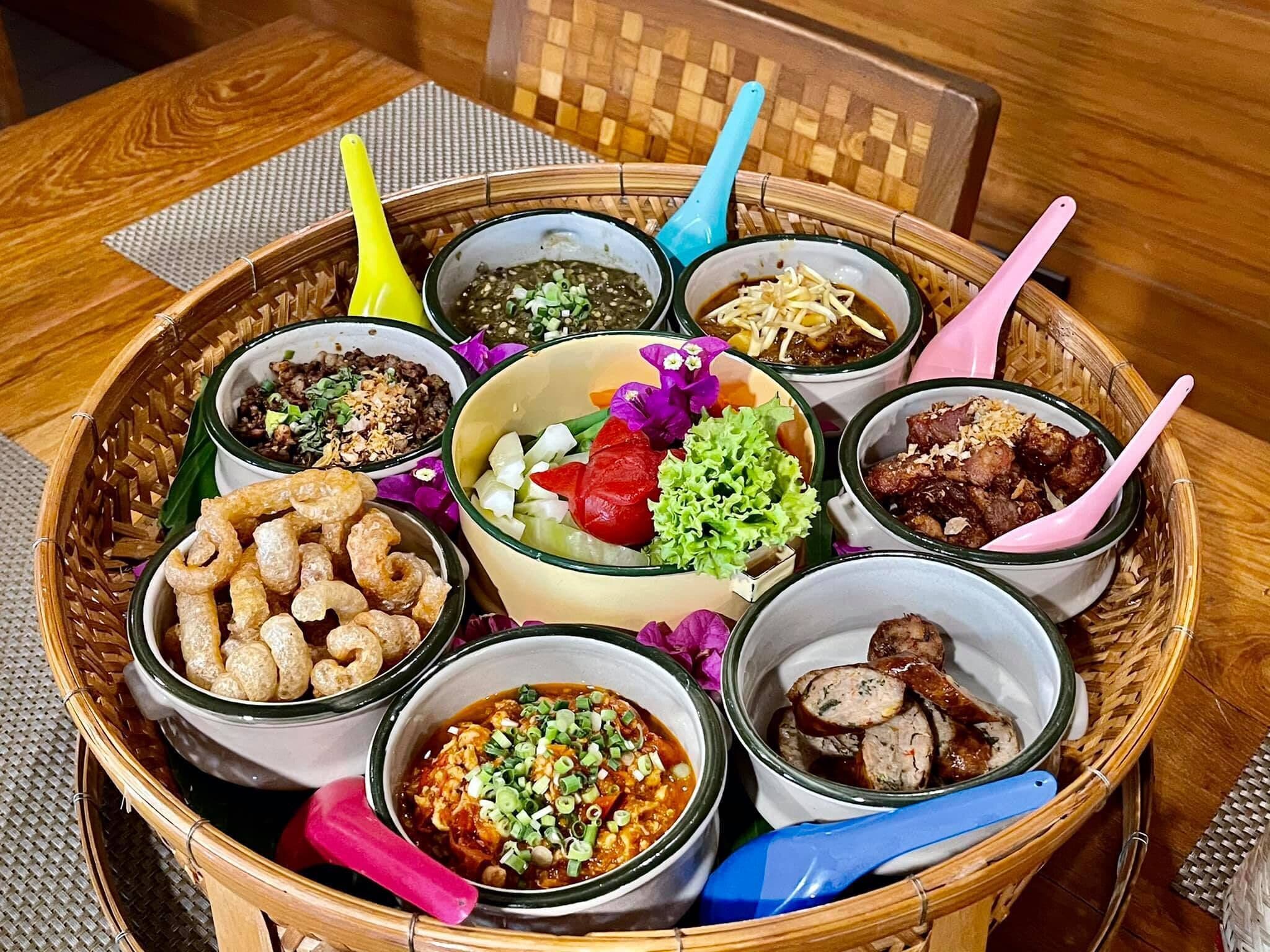 Une variété de plats présentés dans un panier tressé, accompagnés de cuillères colorées.
