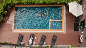 An indoor swimming pool with a person swimming, surrounded by lounge chairs and a small hot tub. - Cmor by Recall Hotels, Chiang Mai (Chiang Mai)