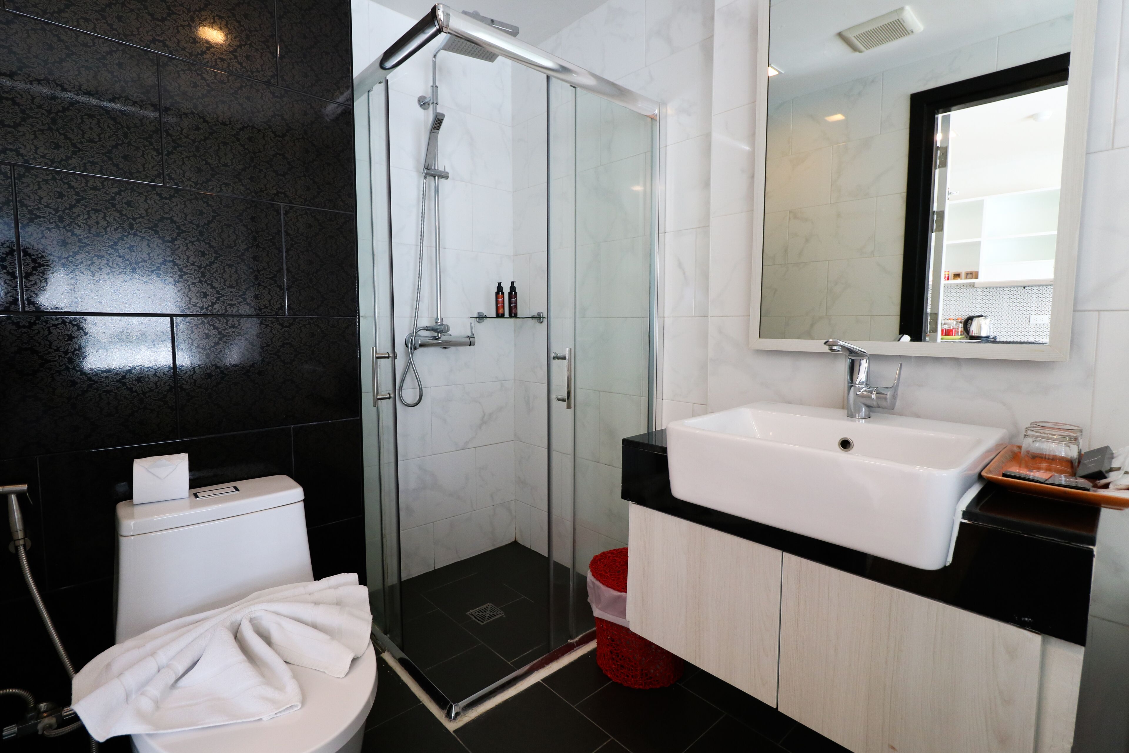 A modern bathroom with a glass-enclosed shower, a white sink, and a mirror above it.