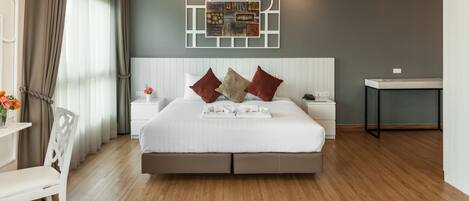 A modern bedroom with a large bed, a bedside table, a nightstand, a chair, and a wall art piece.