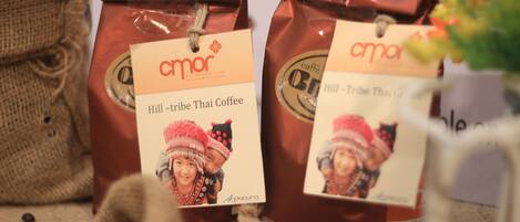Deux sacs de café dont les étiquettes indiquent « Café thaï des tribus montagnardes » et « Andacura ».