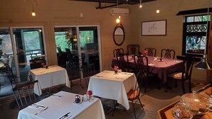 Un restaurante con mesas dispuestas para comer, un amplio ventanal con vistas y un letrero en la pared.