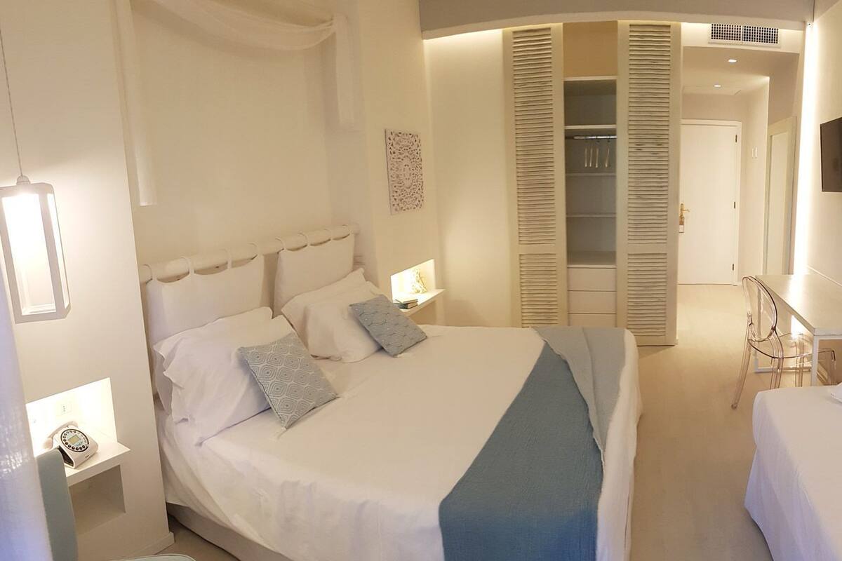 A bedroom with a bed, bedside tables, a TV, and a walk-in closet.
