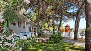 Ett bostadsområde med ett vitt hus, en lekplats med orangefärgad utrustning och en röd lusthus.