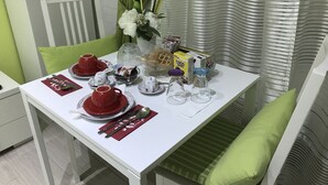 A dining table set with red and white dishes, a vase with white flowers, and a box of Coco Pops cereal. - Vatican City Holidays (Rome)