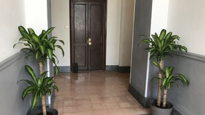 A hallway with two potted plants on either side, a double door at the end, and a patterned floor. - Vatican City Holidays (Rome)