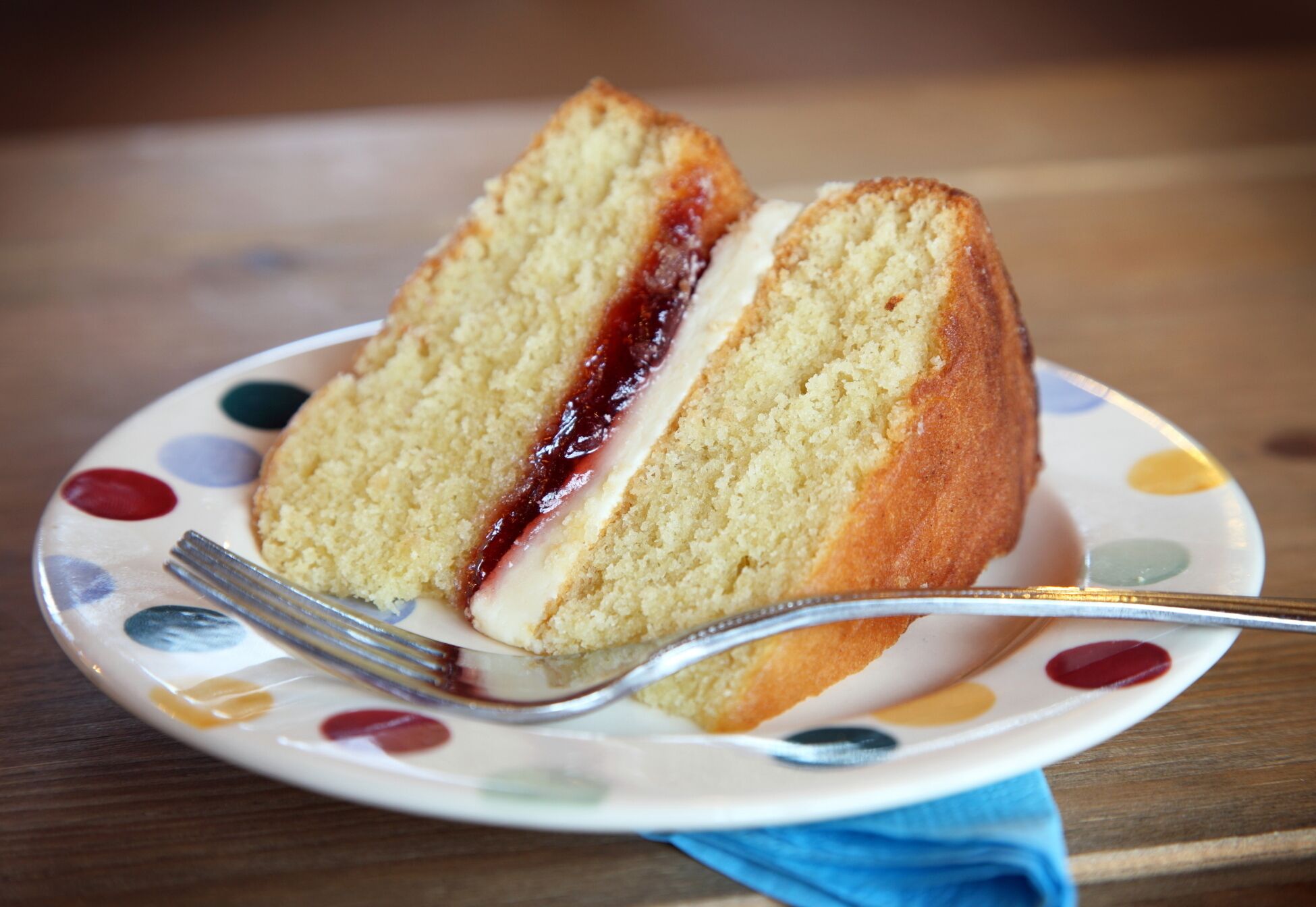 A slice of cake with jam on a plate with a fork.