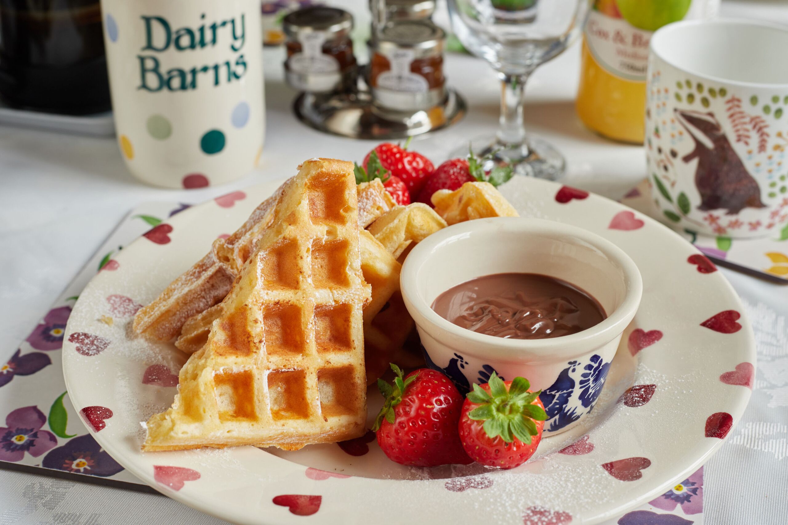 Un plato con gofres, fresas y salsa de chocolate.