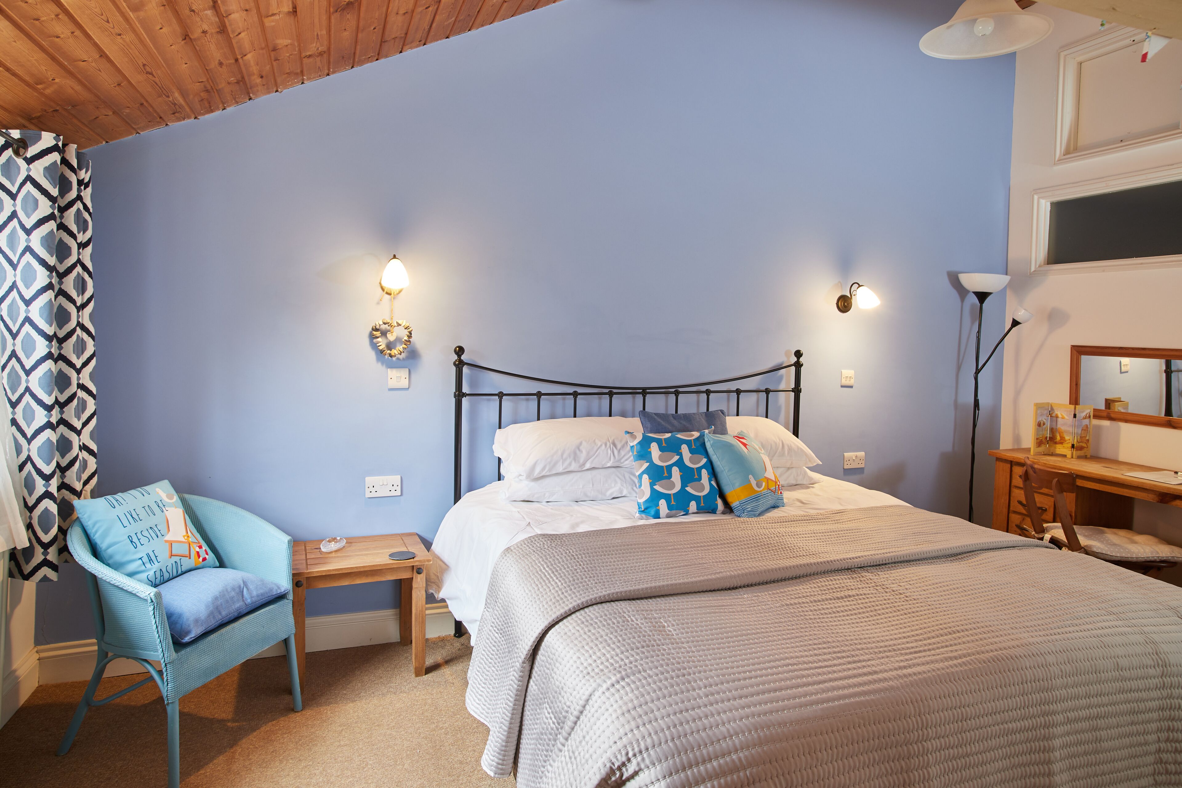 Une chambre à coucher avec un lit, une chaise, un bureau et une lampe.