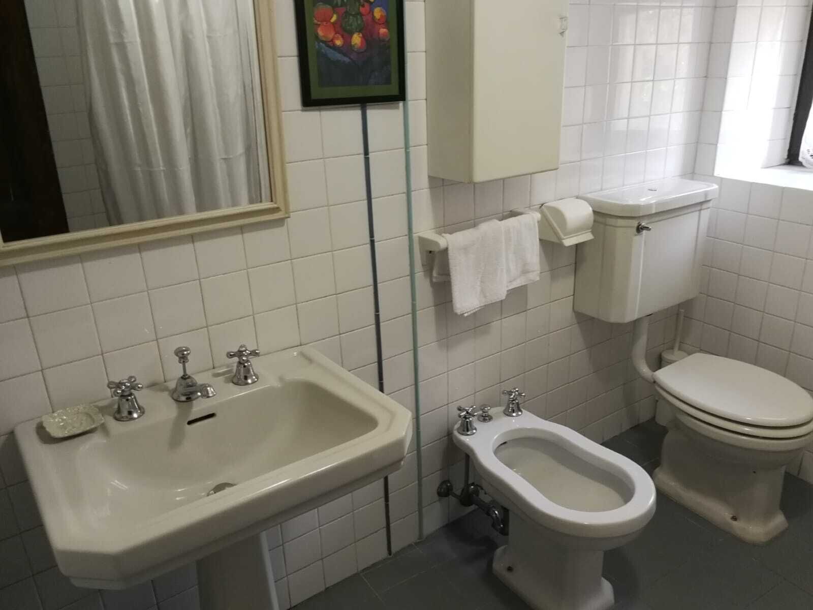 A bathroom with a sink, bidet, toilet, and a mirror.