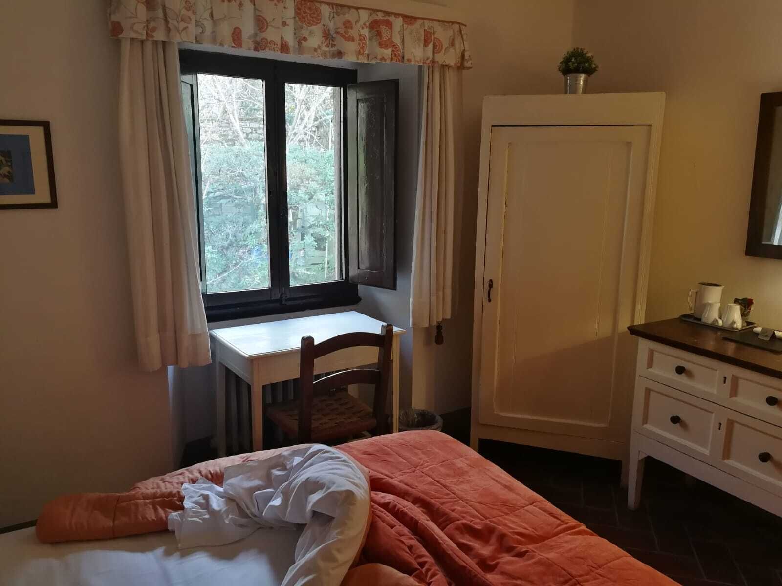 Une chambre à coucher comprenant un lit, un bureau avec une chaise, une armoire et une fenêtre avec des rideaux.