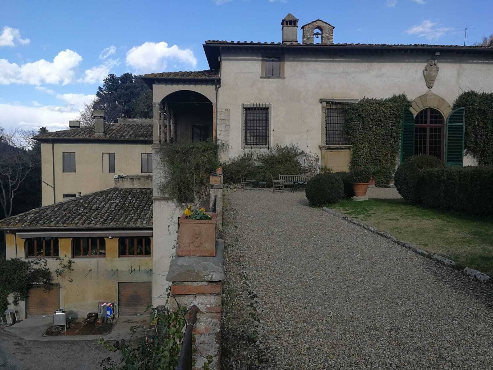 Un edificio con camino de grava, un pequeño jardín y un banco.