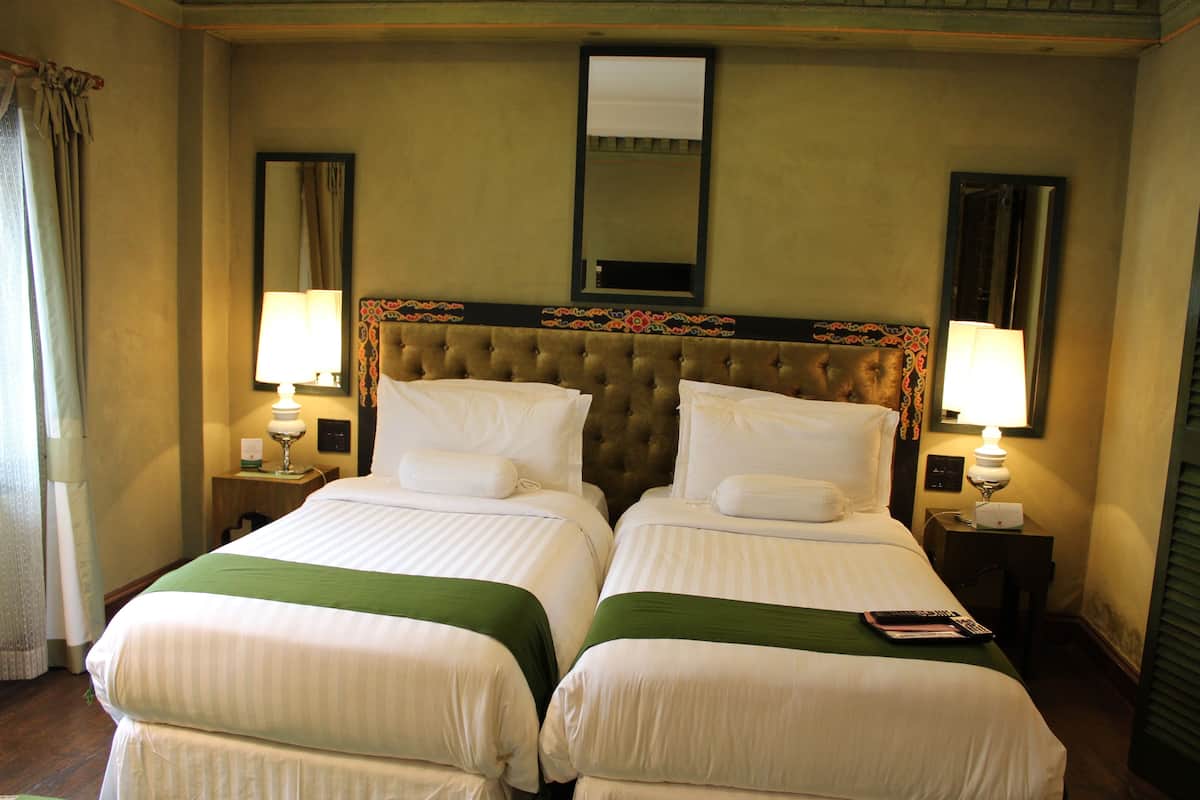 A hotel room with two beds, a large mirror, and two bedside lamps.