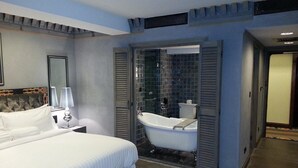 A hotel room with a large bed, a bathroom with a bathtub, and a shower area. - Druk Hotel (Thimphu)