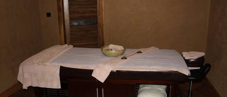 A massage table with a towel, a bowl, and a bottle.