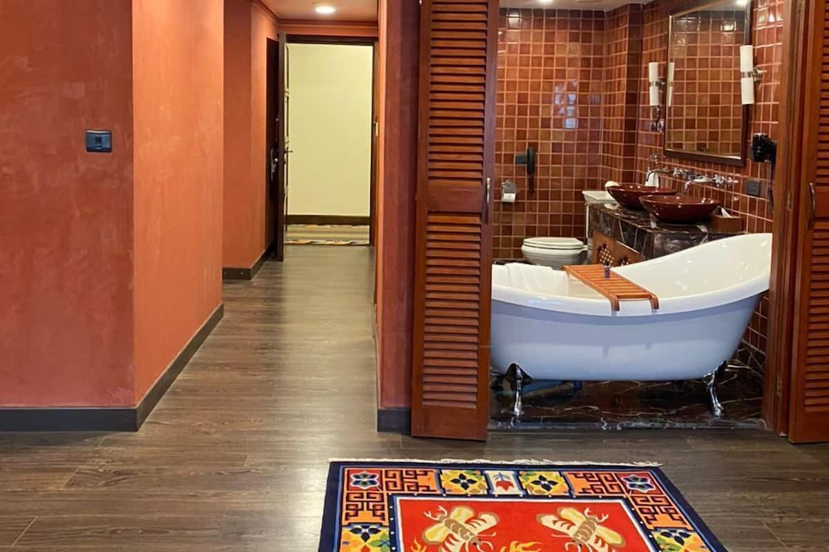 A traditional Japanese-style bathroom with a bathtub, a sink, and a mirror.