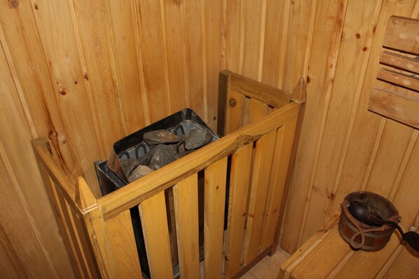 A wooden cabin interior with a metal bin and a wooden bucket.