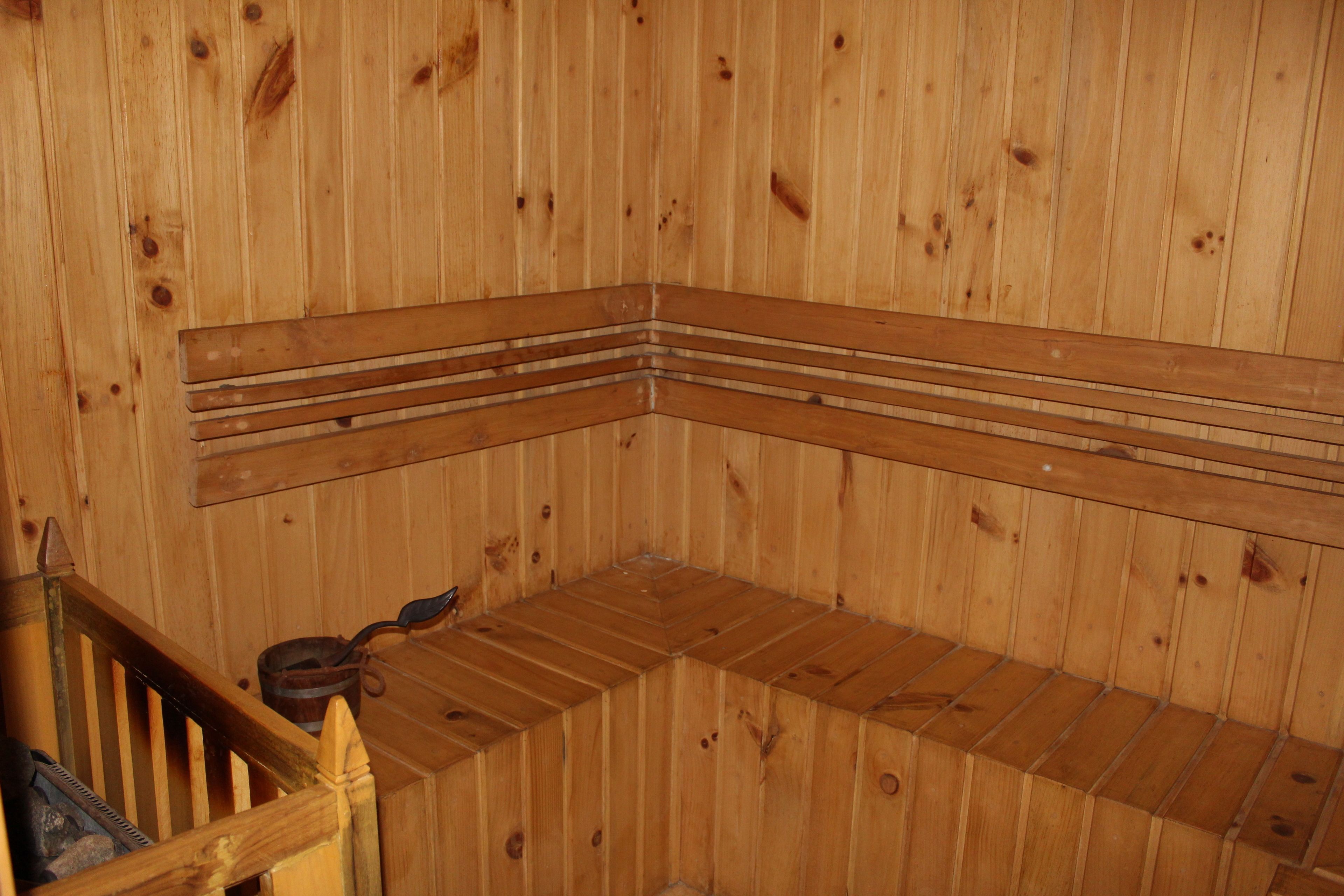 Un sauna en bois avec un banc et une rambarde en bois.