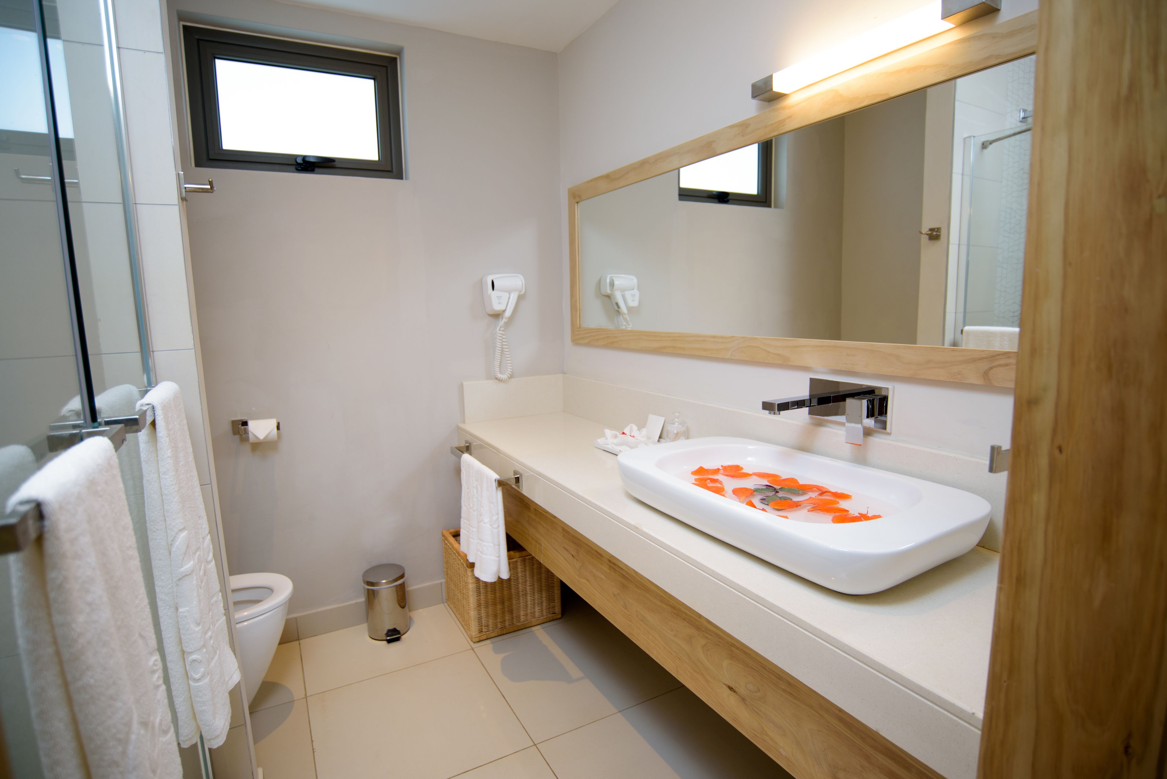 A modern bathroom with a white sink, a large mirror, and a toilet.