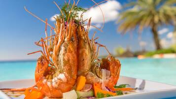 A plate of cooked shrimp with vegetables, set against a beach background.
