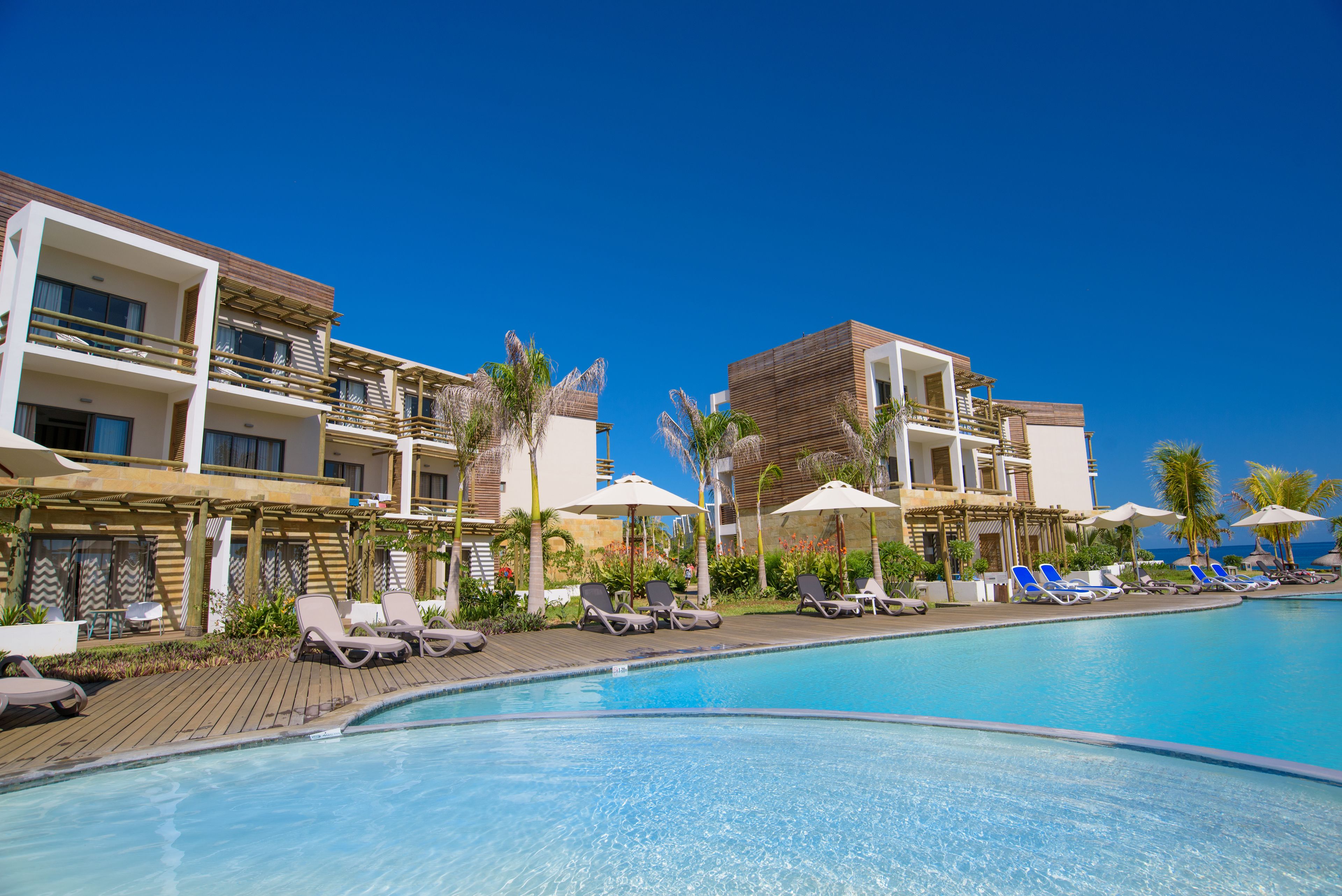 Un hotel con piscina, tumbonas y sombrillas.
