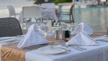 Mesa lista para comer con vistas a la piscina y palmeras.