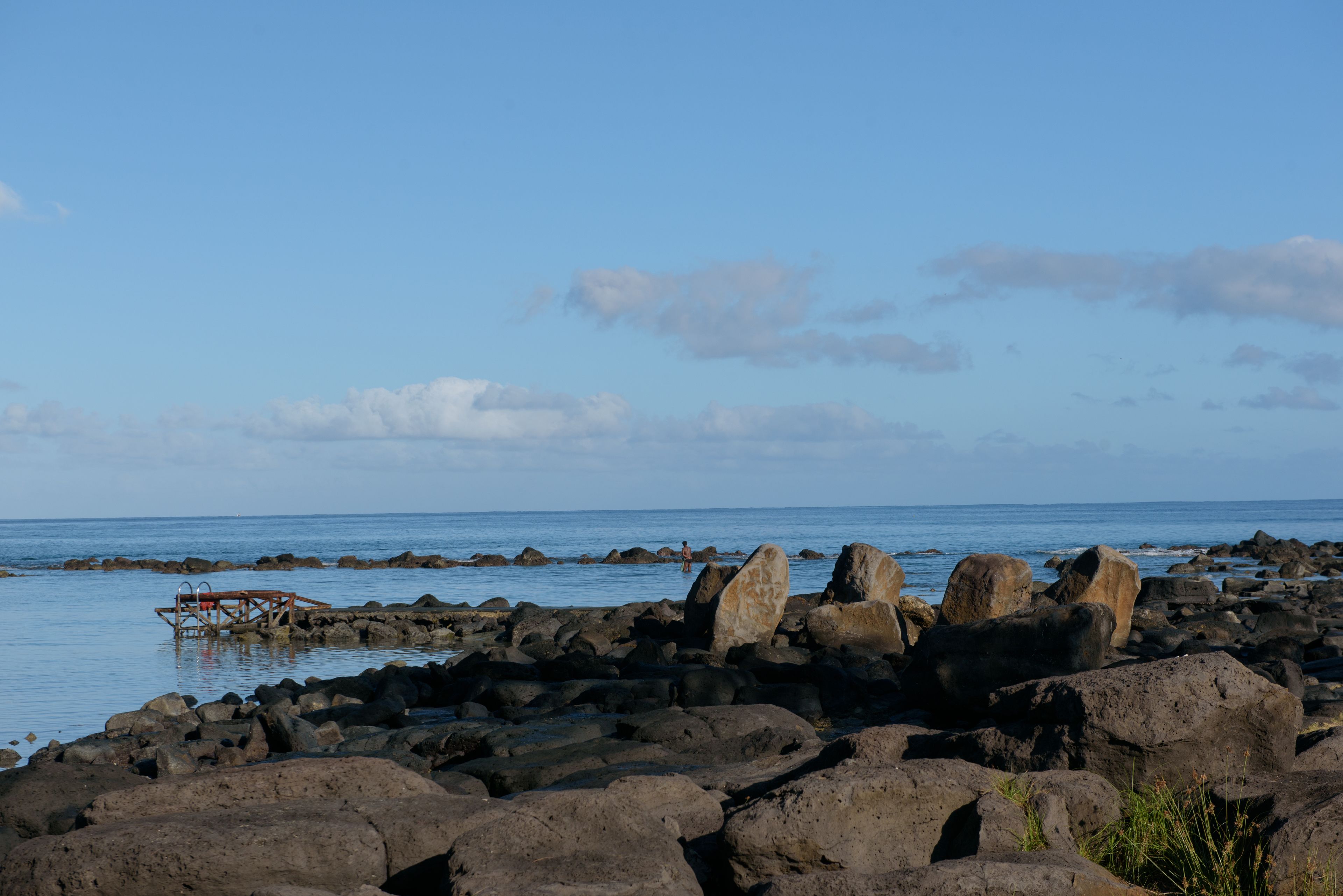 A rocky shoreline with large boulders and a wooden structure.