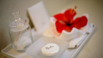 A small white tray with a glass jar, a white bottle with the name "Anelia," and a red hibiscus flower.