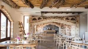 Un restaurant doté d’arches en pierre, de tables en bois et de chaises en osier.